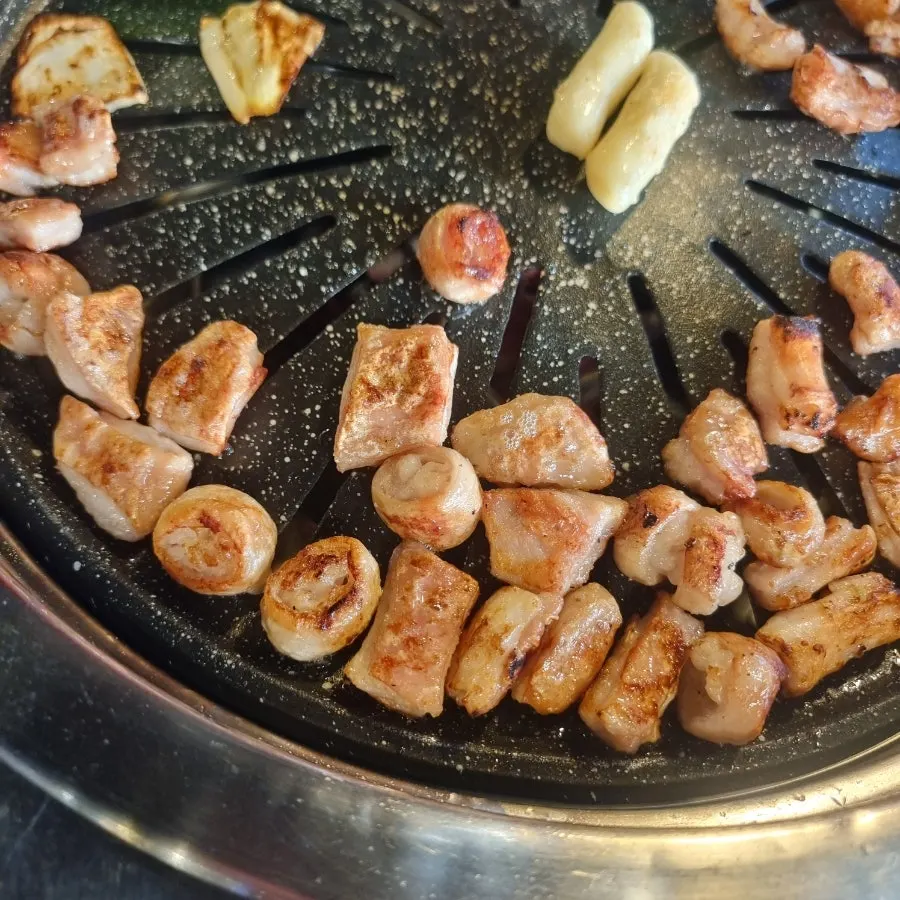 Chopsticks picking up a well-grilled piece of makchang