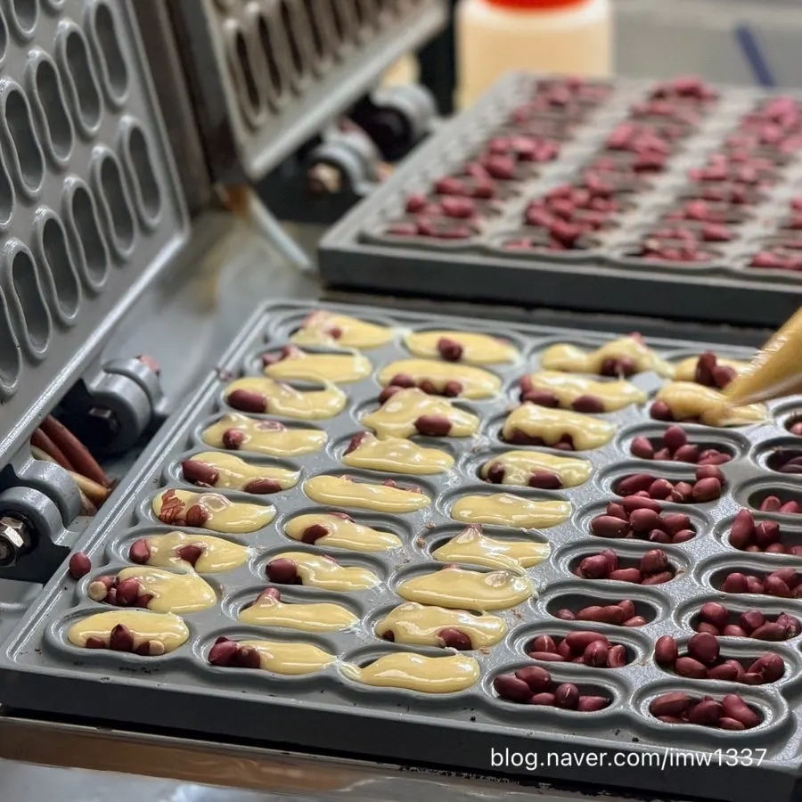 Whole peanuts being placed onto peanut bread batter