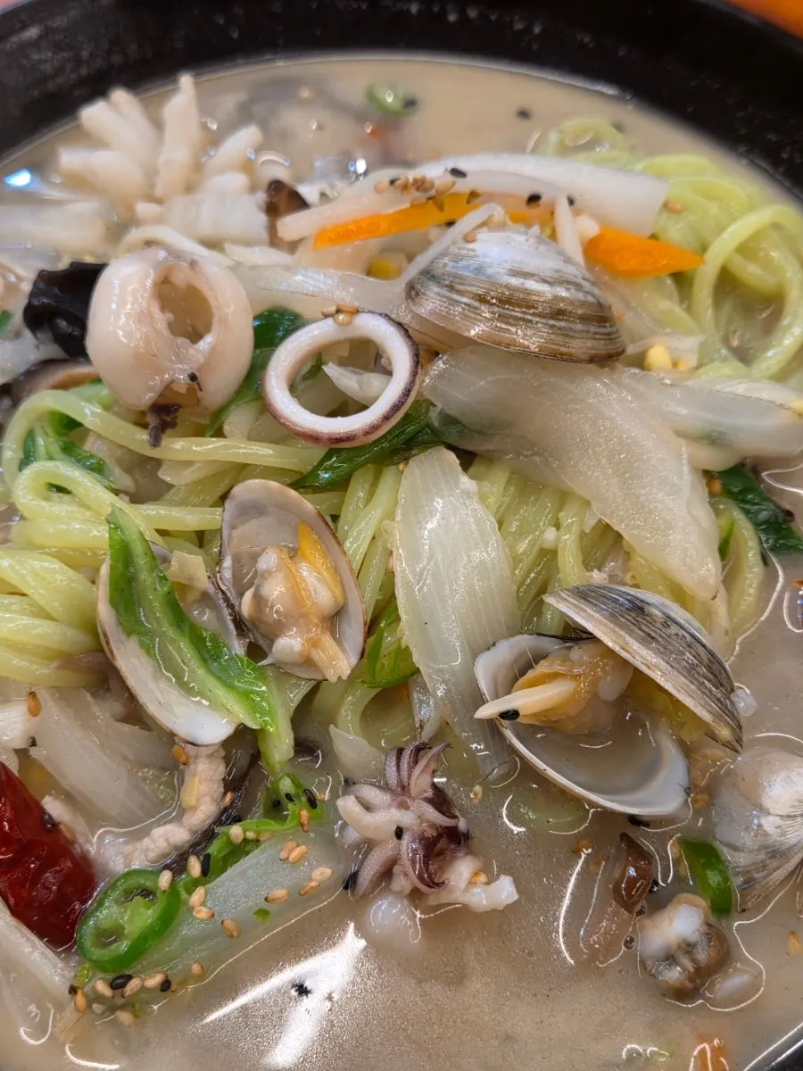 Pale green noodles and generous ingredients in white jjamppong
