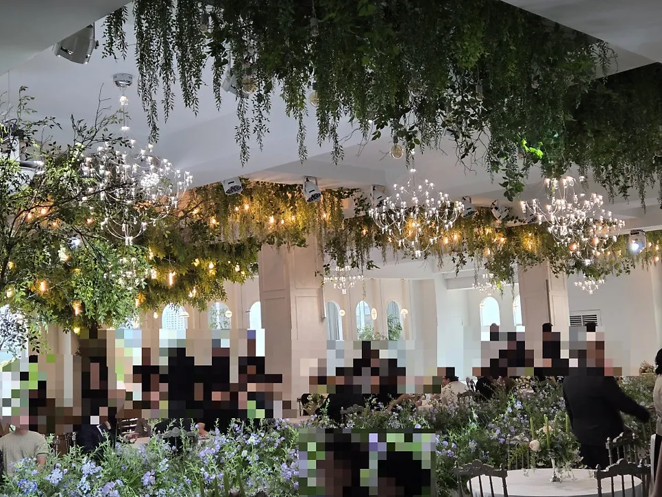 초록 생화와 샹들리에로 장식된 실내 예식 홀