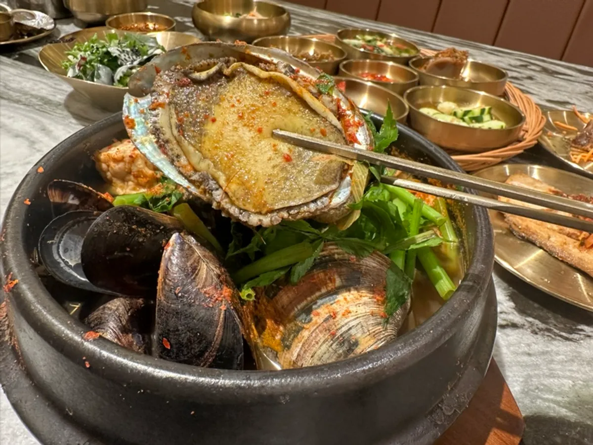 A large abalone on top of the seafood ttukbaegi