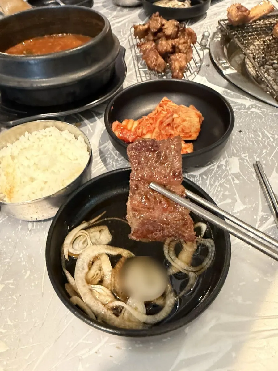 A piece of pork galbi held with tongs