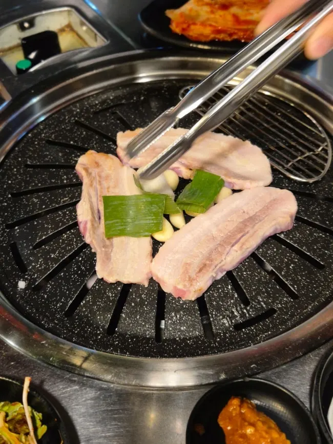 Pork belly and vegetables arranged in a triangle on the grill