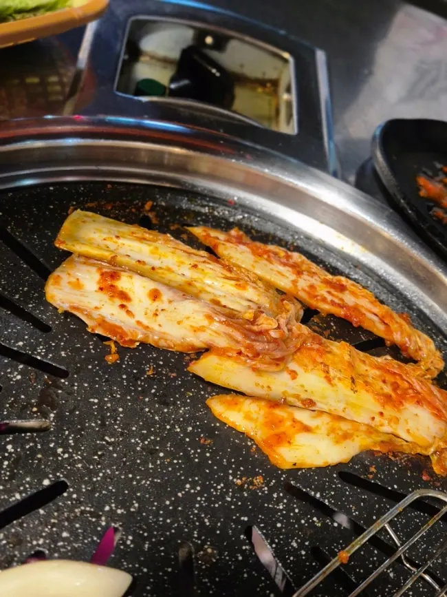 Kimchi grilled alongside pork belly on the pan
