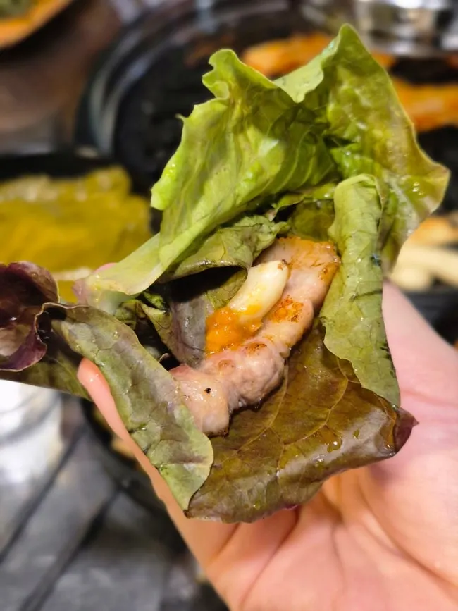A bite of Daraewon Makchang pork belly with ssamjang dipping sauce