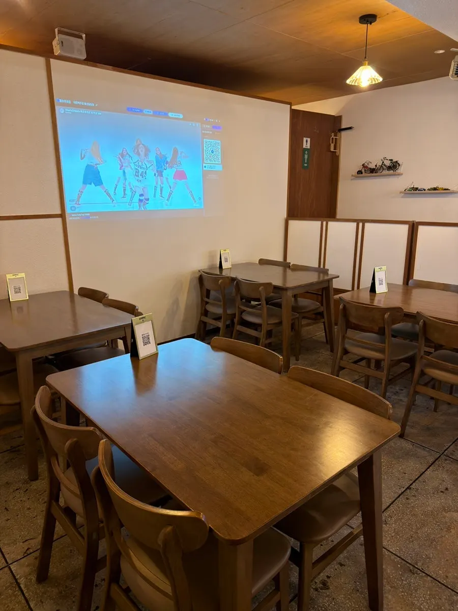 Wood-tone seating and a large screen inside the venue