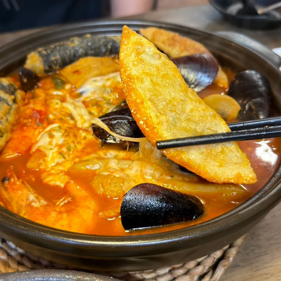 A plate of seafood cheese tteokbokki with plenty of broth