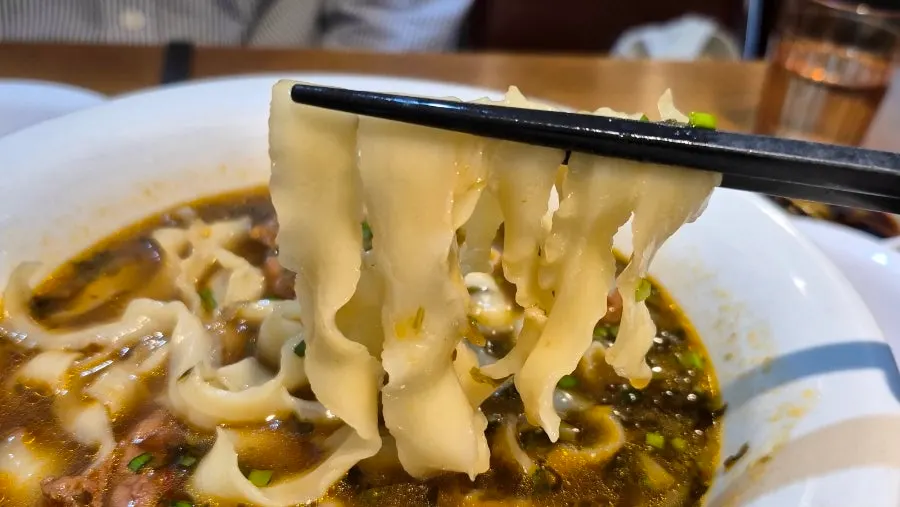 Wide knife-cut noodle strands in rich beef broth