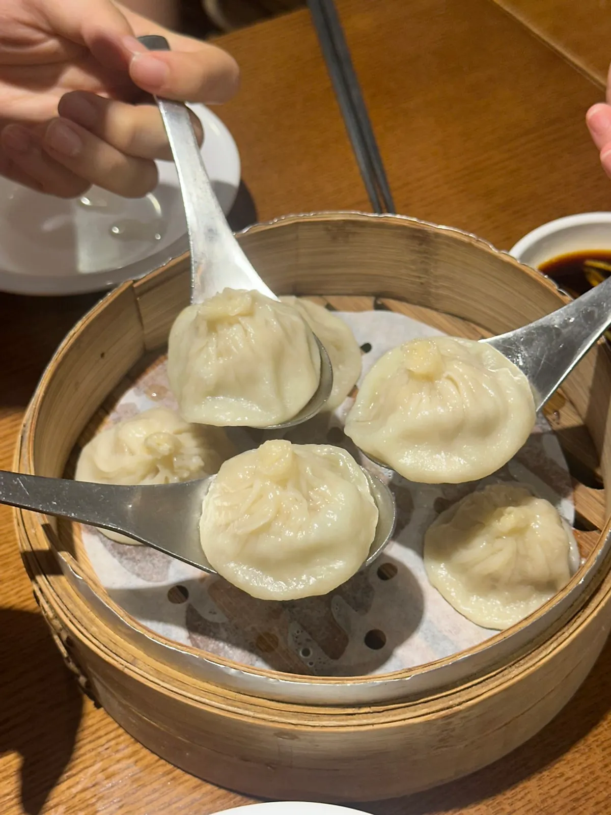 Xiaolongbao with broth flowing from a bitten wrapper