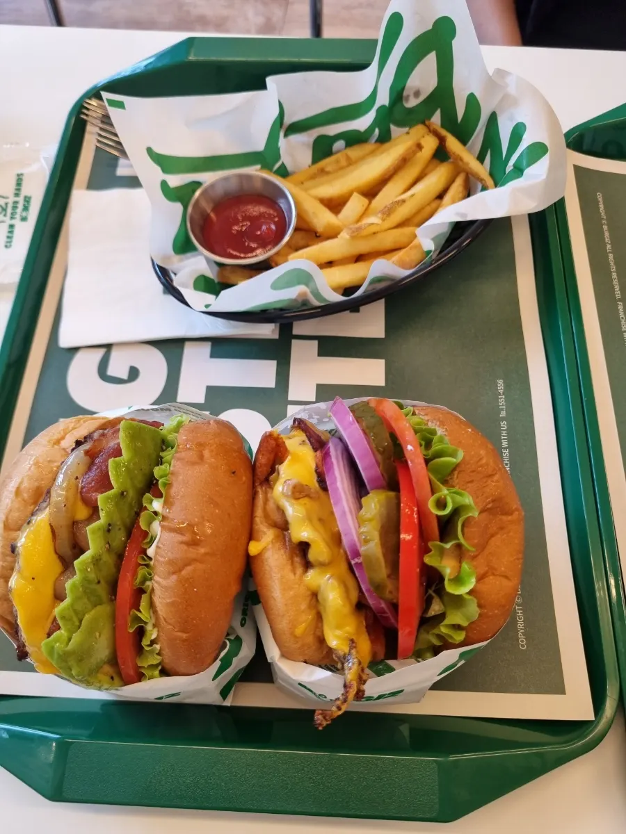Table with three types of burgers, fries, and sparkling water