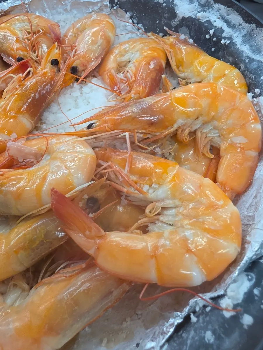 Live shrimp being salt-grilled on a bed of coarse salt