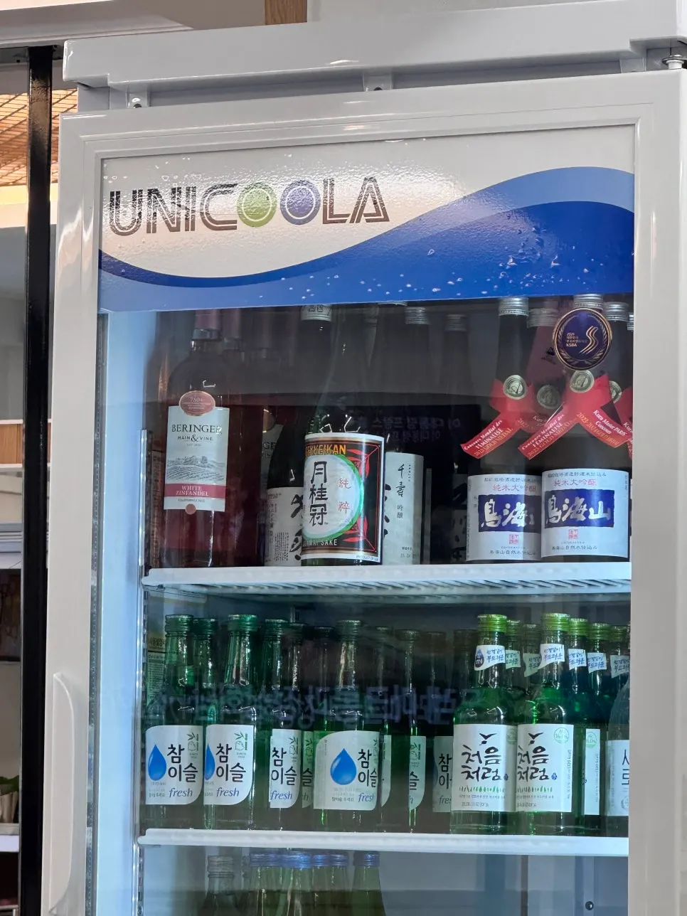 A drinks fridge stocked with wine, sake, and traditional liquor