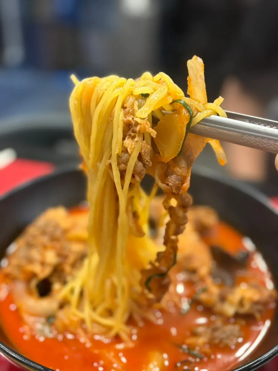Chopsticks lifting toppings from the meat jjamppong