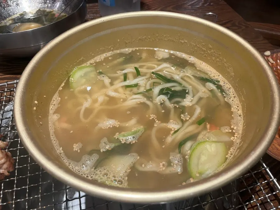 Spicy market-style kalguksu noodles served bubbling in a bowl