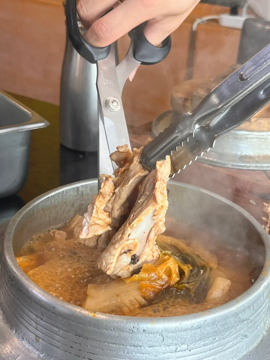 Cutting the whole kimchi in the galbi kimchi stew with scissors