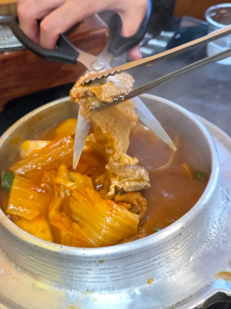 Cast-iron-pot galbi kimchi jjigae simmering at the table