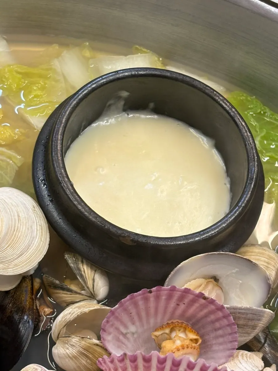 Broth full of hard clams and scallops in the hot pot