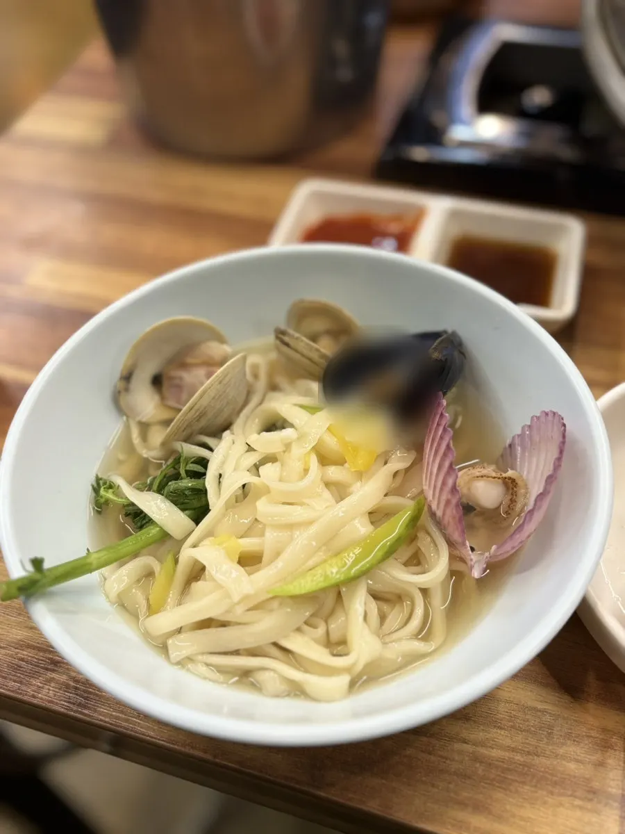 Clam kalguksu boiling on the neighboring table's burner