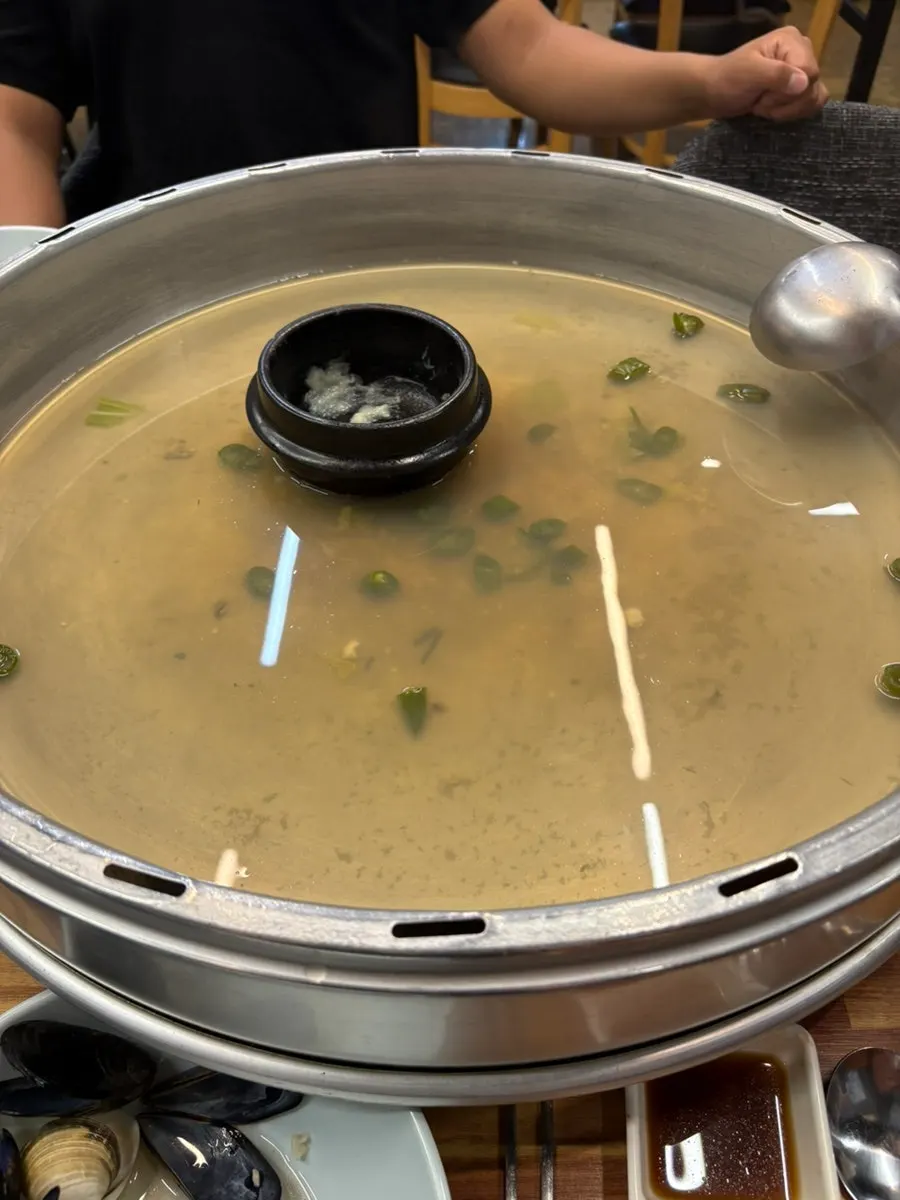 Clam kalguksu ladled into a serving bowl