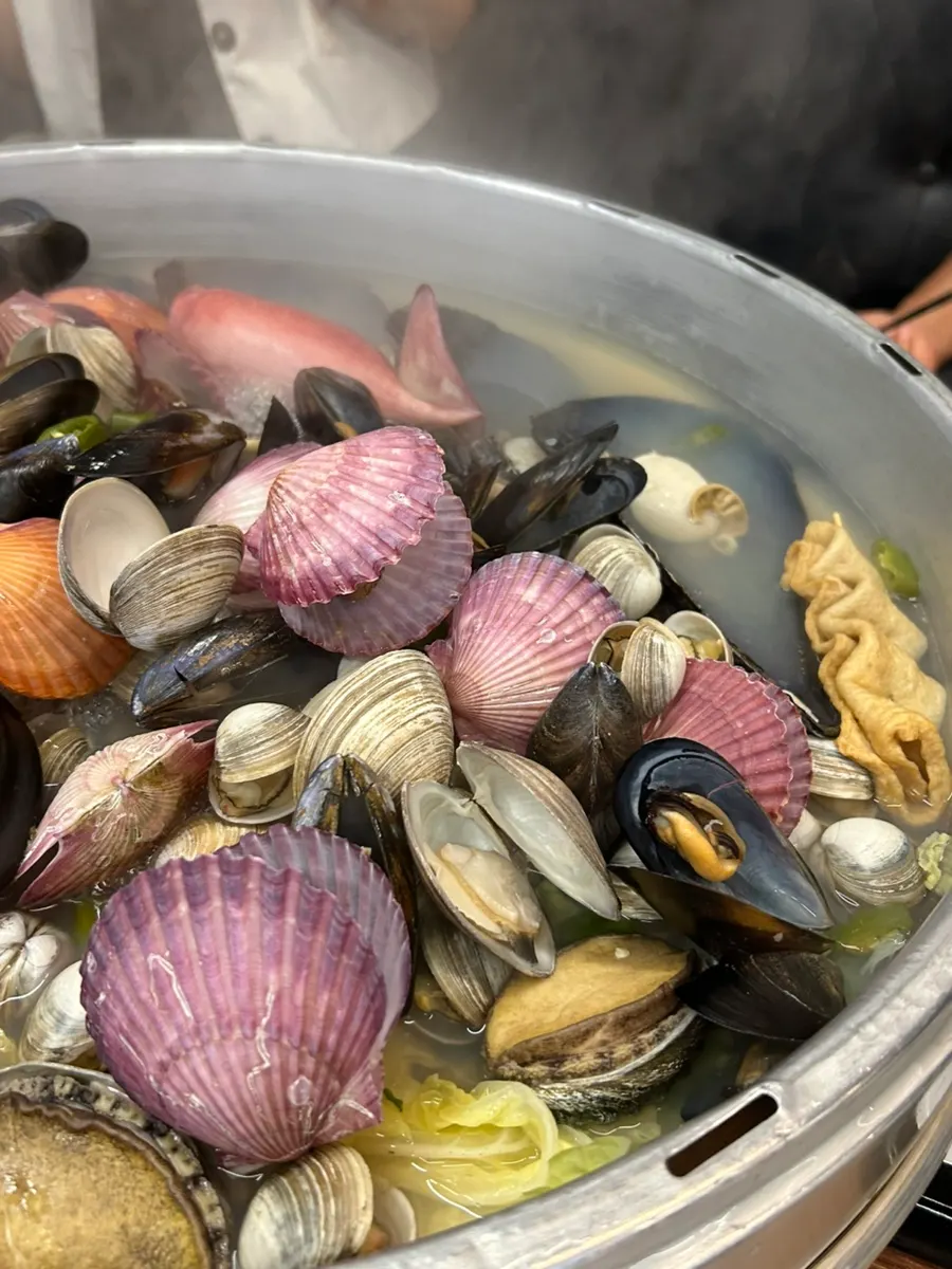 Hot pot topped with scallops, razor clams, abalone, and cheese