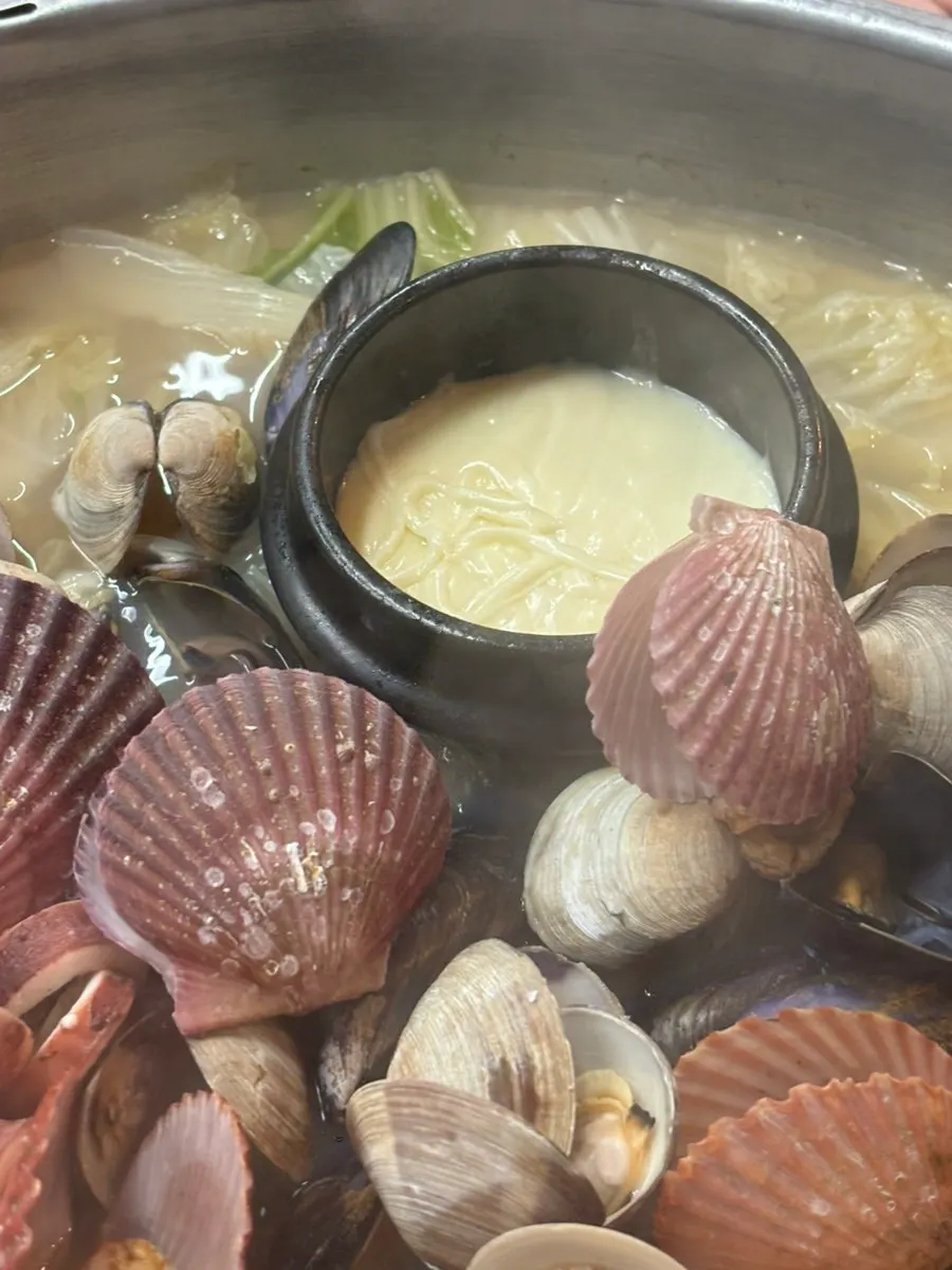 Clams being dipped into vinegar-chili sauce and soy sauce