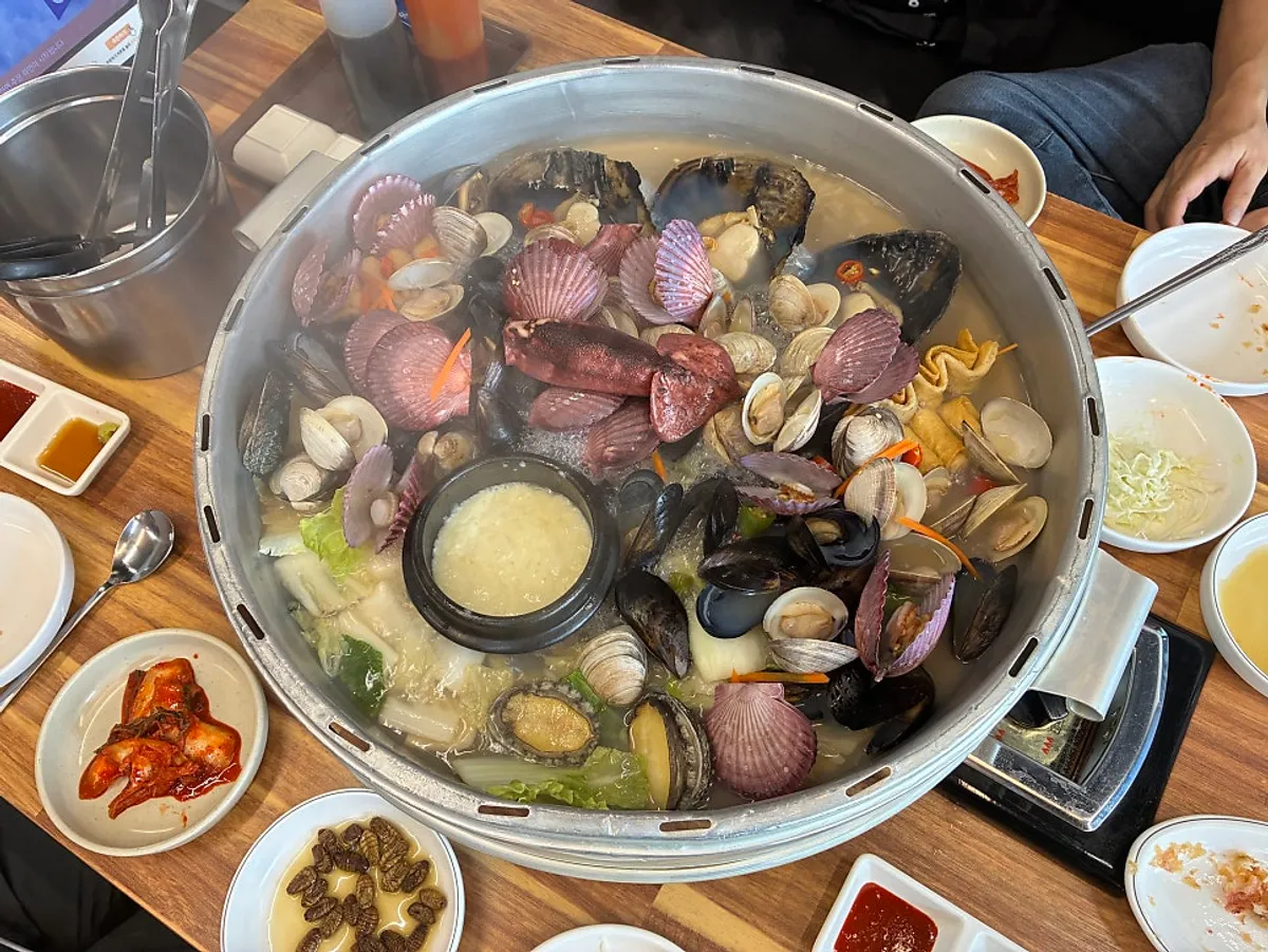 Hot pot lid opened to reveal clams packed inside