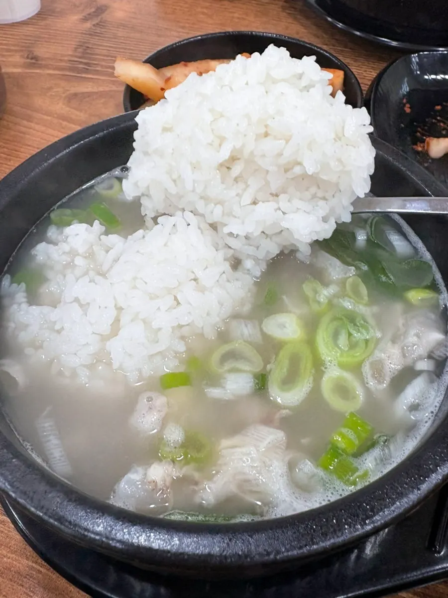 A spoonful of rice mixed into broth topped with silbi kimchi