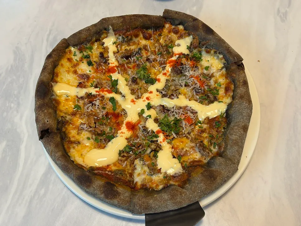 Fire-grilled chopsteak pizza on a squid ink dough