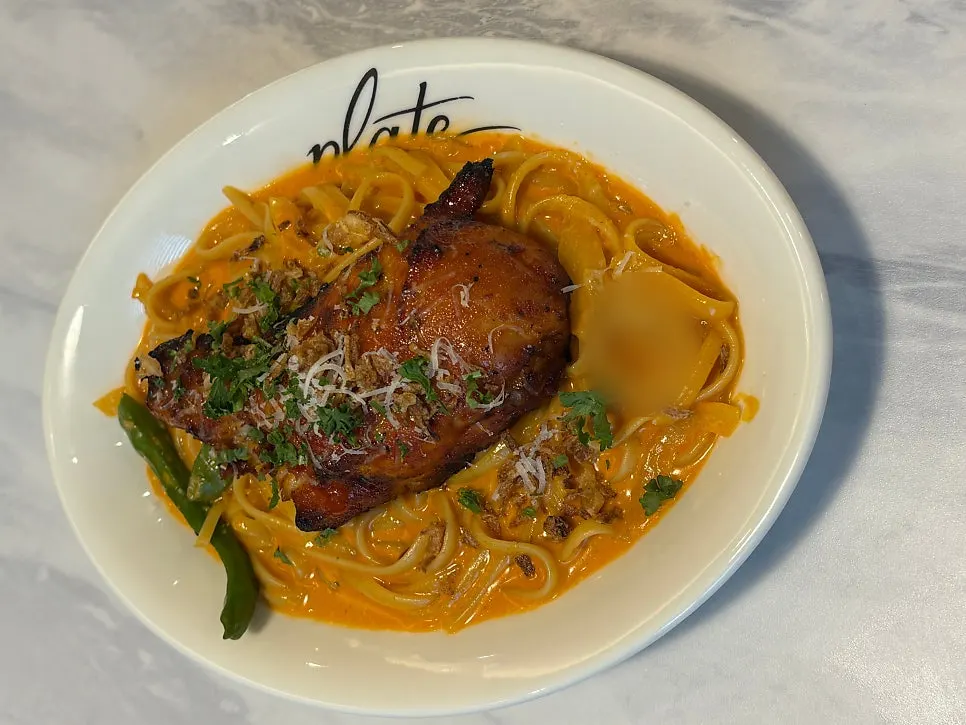 Spicy rosé chicken linguine pasta topped with a whole roasted chicken leg
