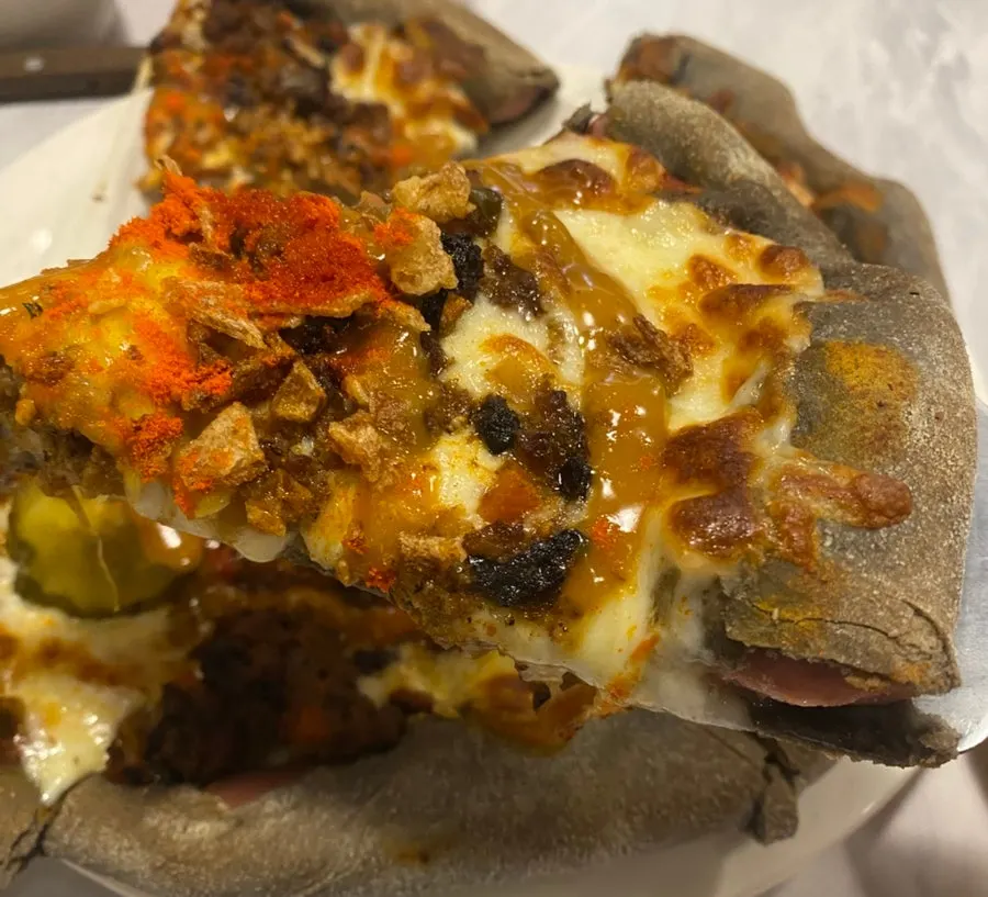 A slice of beef cheddar cheese pizza with melted cheese