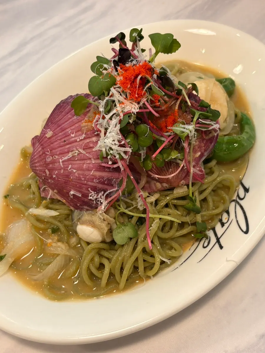 Close-up of scallop uni oil pasta topped with seafood
