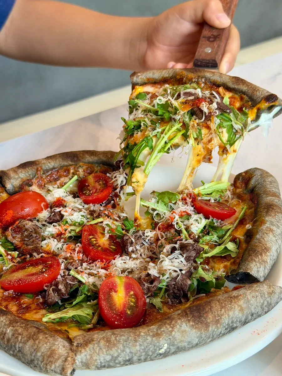 Chapsteak pizza topped with arugula and cherry tomatoes