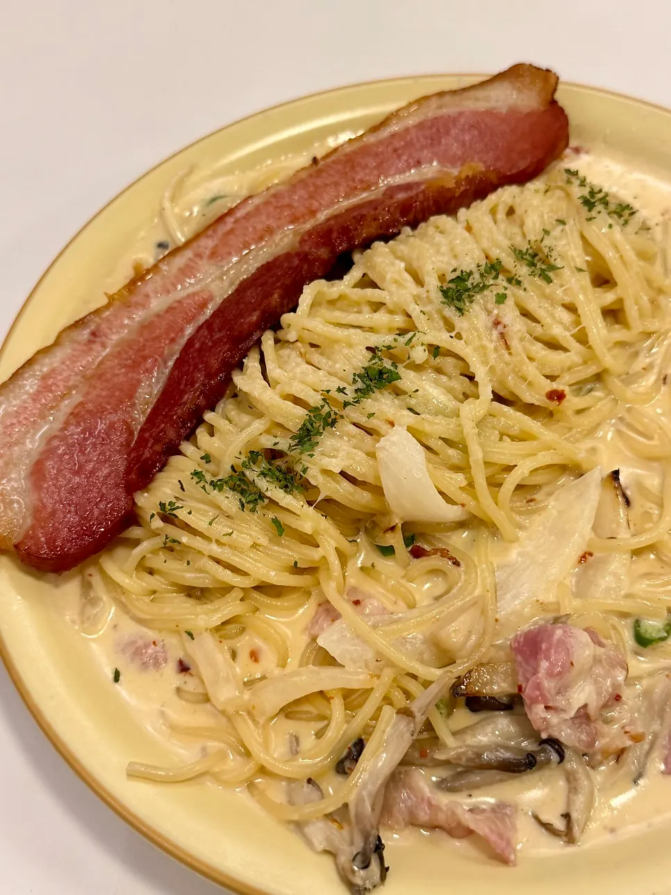 Cream pasta topped with large chunks of bacon