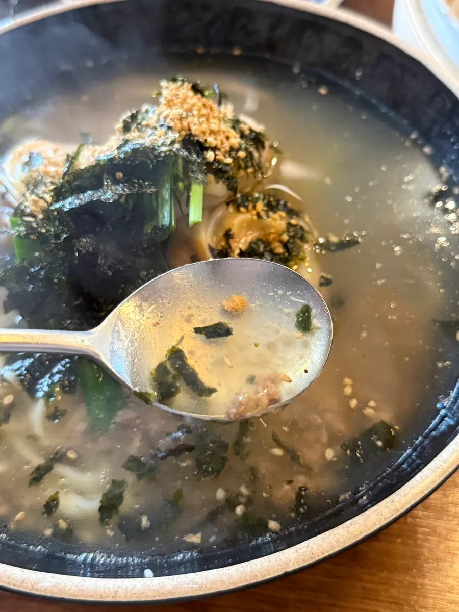 Kalmandoo-guk topped with chives and shredded seaweed