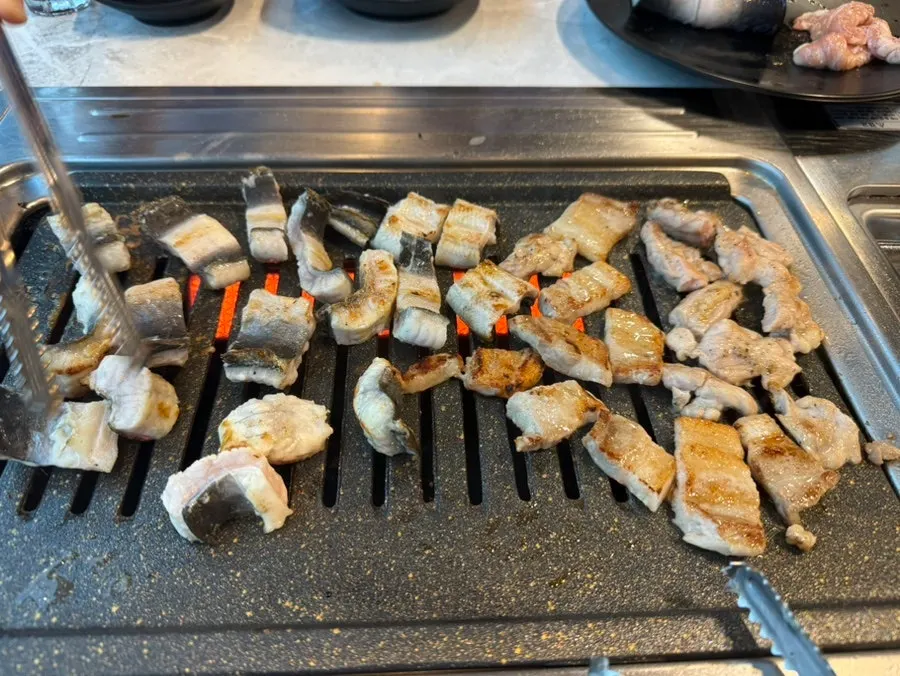 Eel and pork belly cooking on the grill