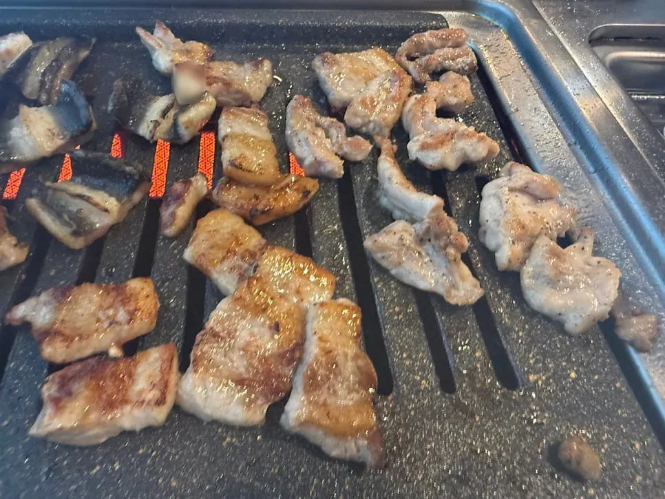 Eel and pork belly cooking together on the grill