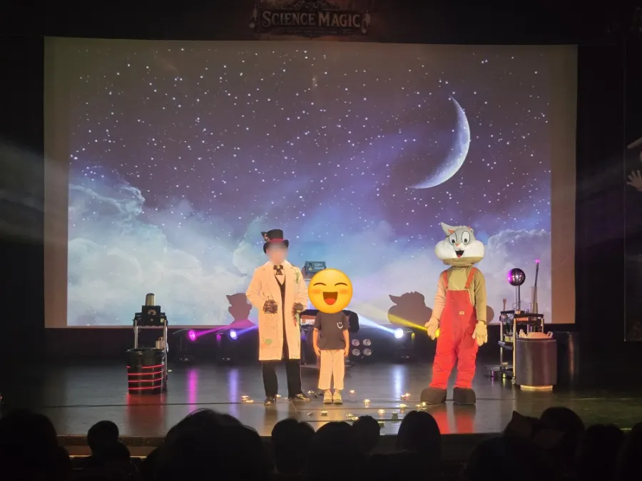A child audience member taking part in a magic trick on stage