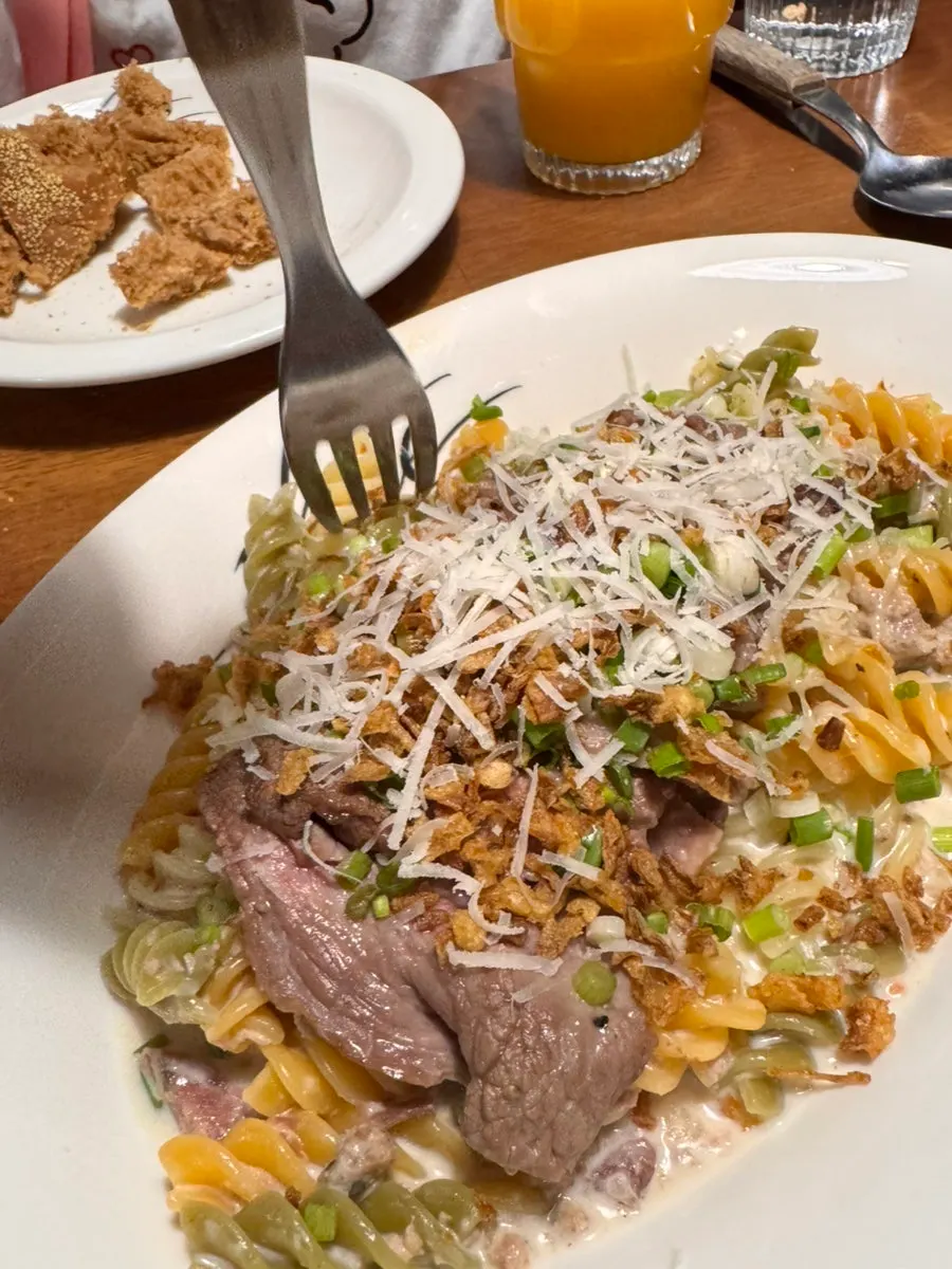 Fresh cream ragù pasta topped with steak