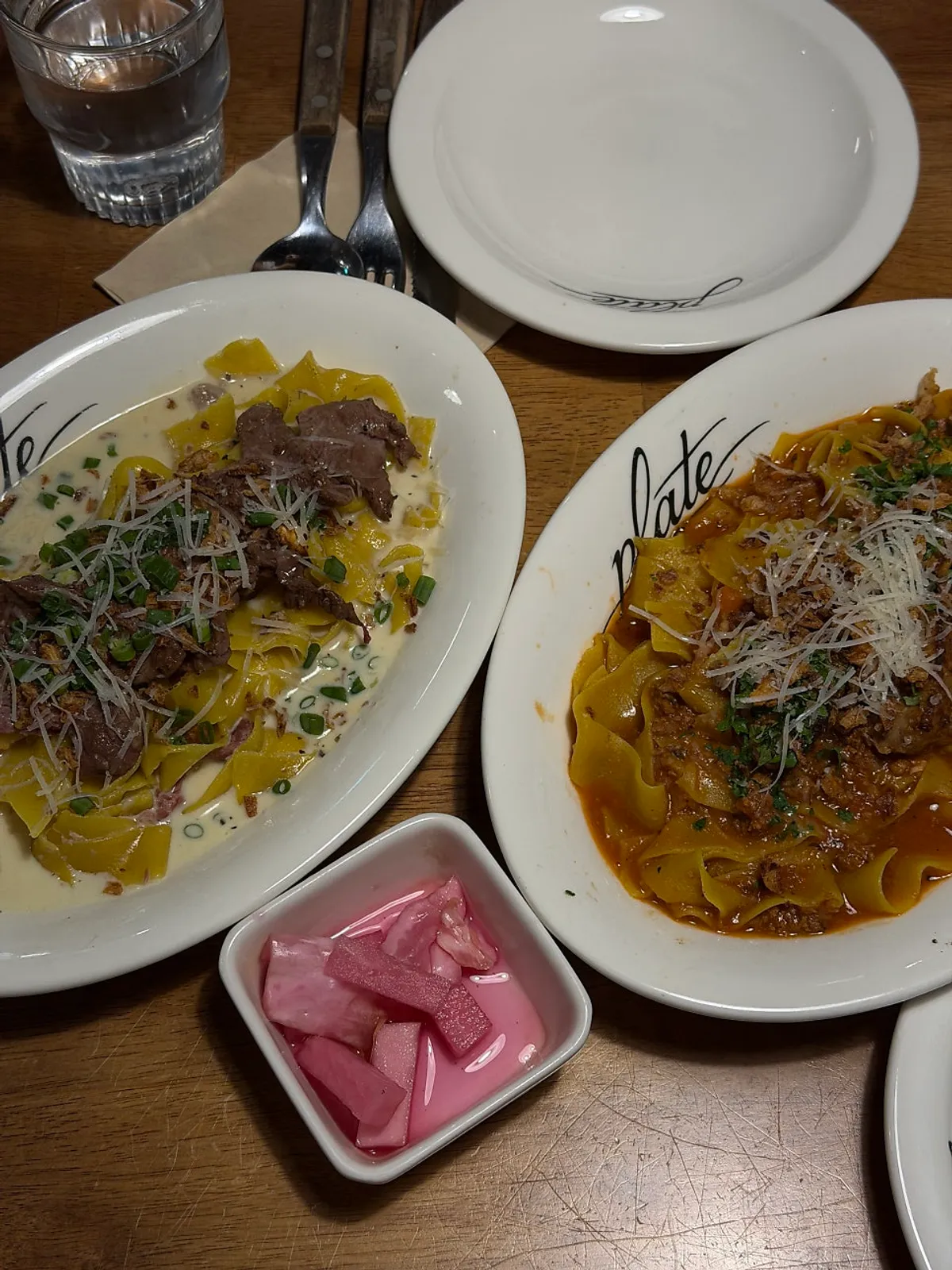 Two plates of pasta on the table together