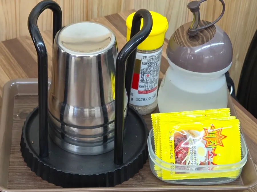 Pepper, vinegar, mustard sauce, and cups set on the table