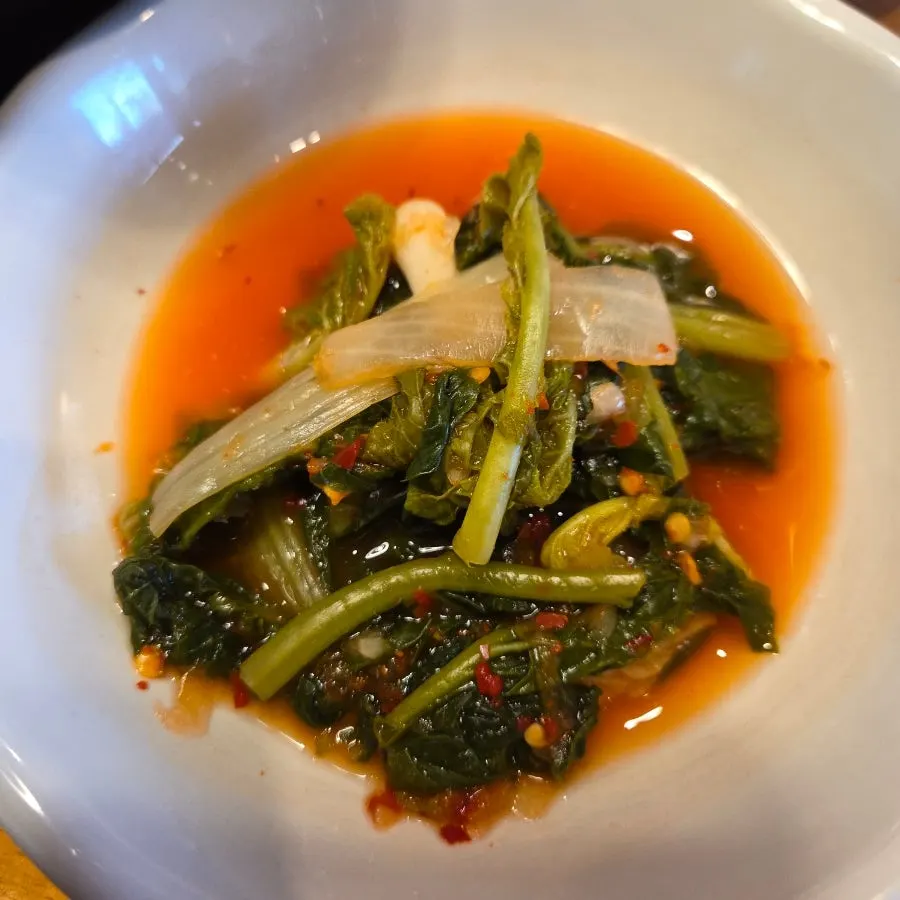 Plates of bean sprouts, yeolmu kimchi, and japchae side dishes