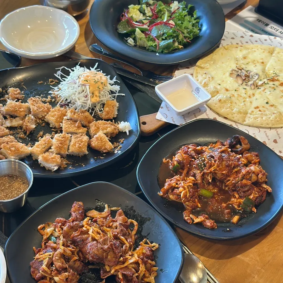 4-person table full of octopus, pork, cutlet, and pizza