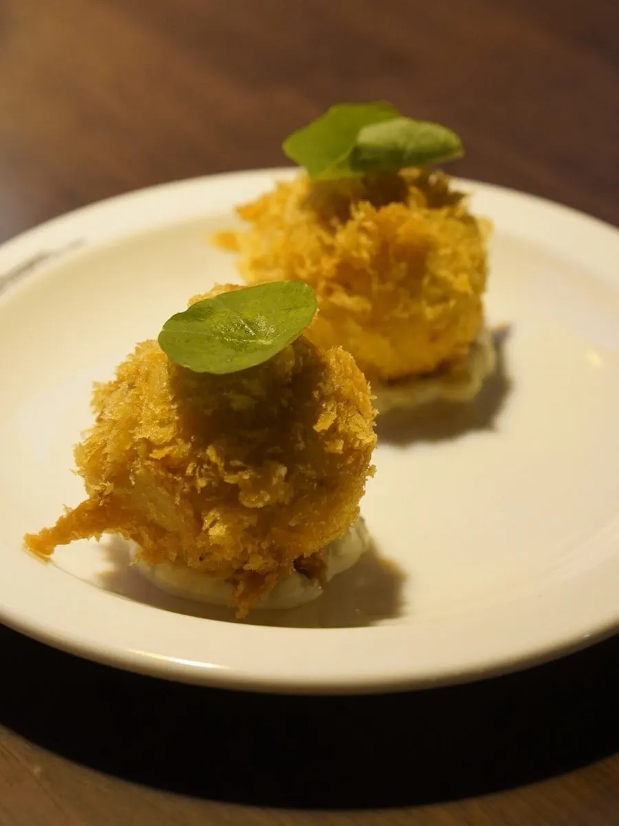 Lobster croquette plate topped with a green leaf