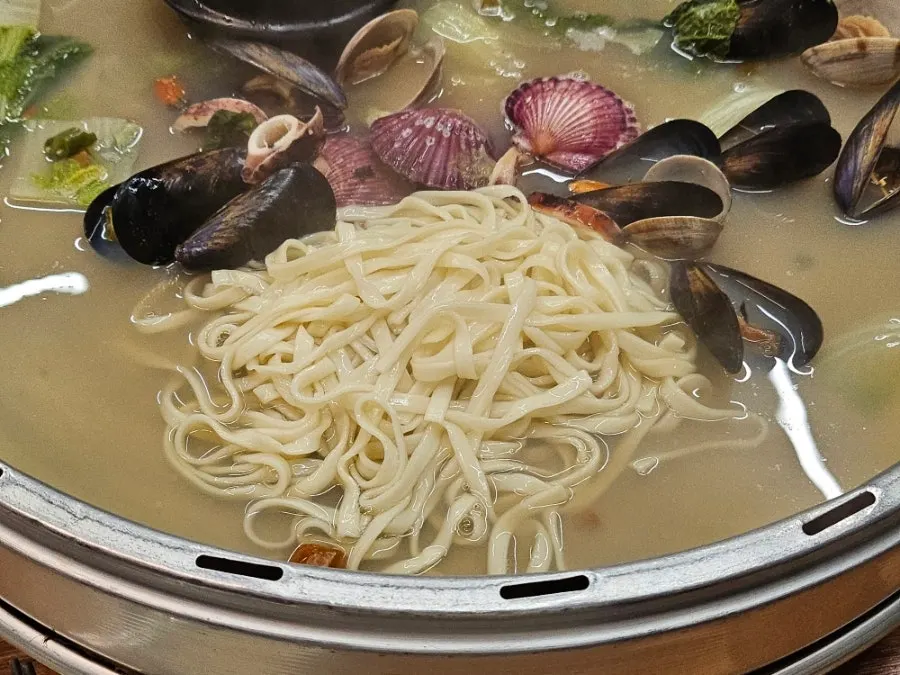 Kalguksu noodles added to the clam hot pot