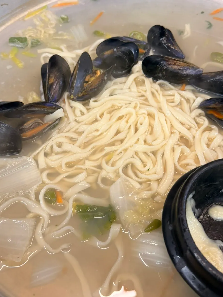 Dipping clams into the stretchy melted cheese clay pot