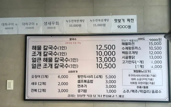 The menu board listing seasonal oyster and prawn dishes at the seafood kalguksu restaurant