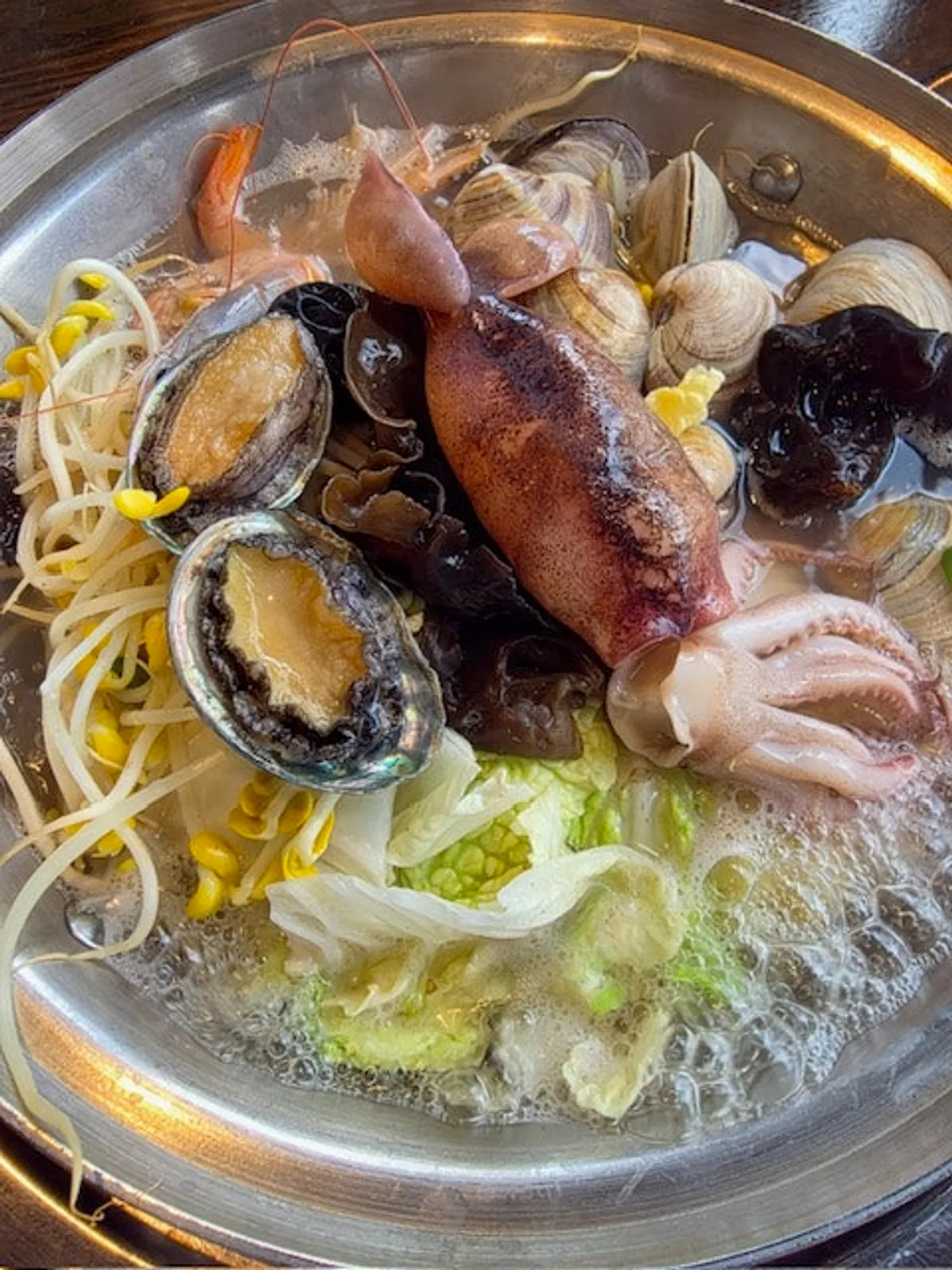 A pot of seafood kalguksu packed full of seafood