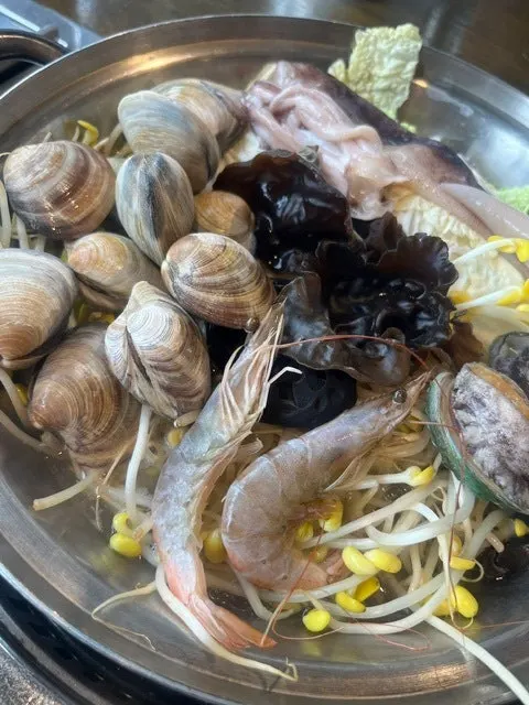 Seafood kalguksu broth simmering with clams