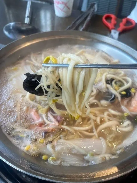 Kalguksu noodles and seafood served on a small side plate