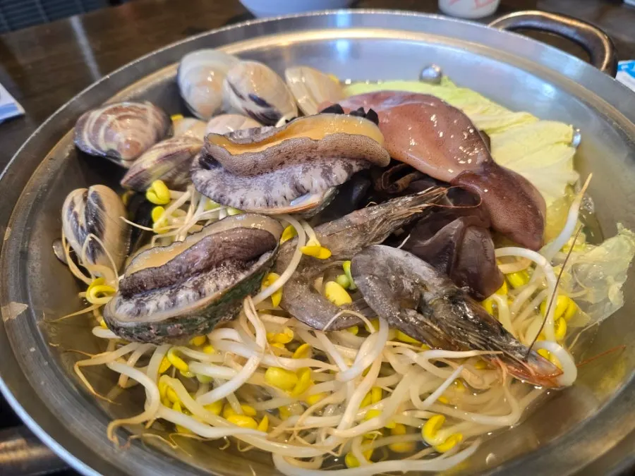 Pot of seafood kalguksu for two loaded with fresh live seafood